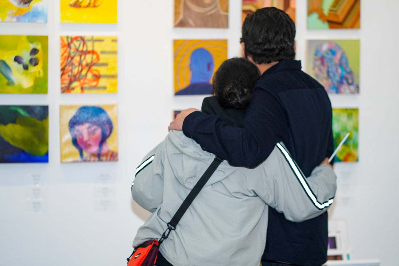 Photograph of a couple hugging and viewing artwok during the "It's BASL, Baby!" group exhibition VIP Young Collectors Event at Voss Gallery, San Francisco, December 4, 2020.